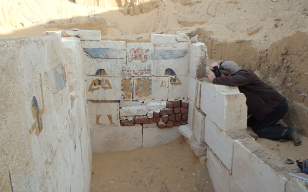 A person photographing ancient Egyptian murals.